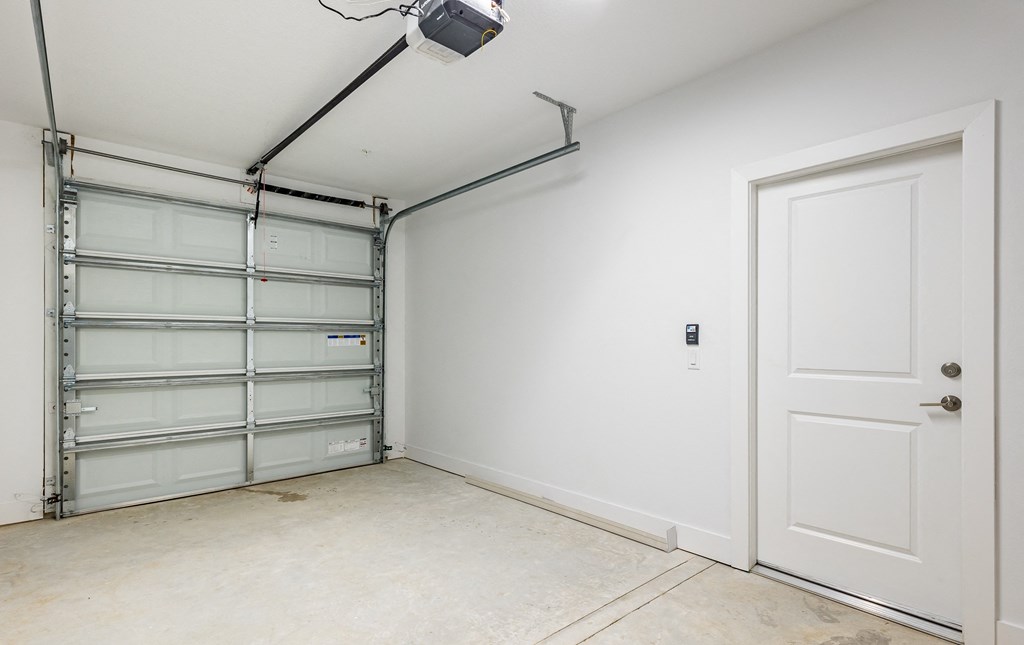 an empty room with a white door and a garage door