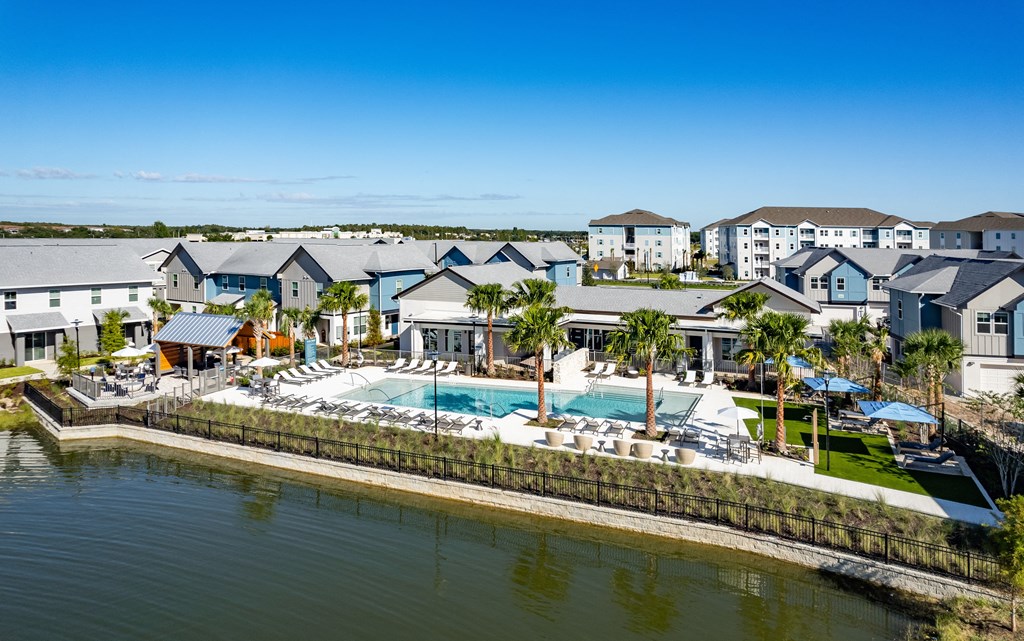 a large swimming pool in front of a row of houses on the water