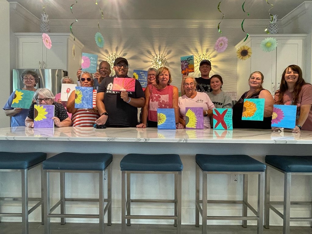 a group of people standing in front of a table with paintings on it