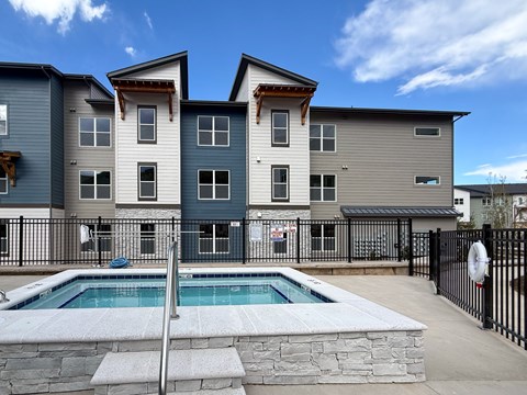 A modern two-story apartment building with a pool in the backyard.