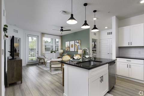 a kitchen and living room with white cabinets and a black counter top