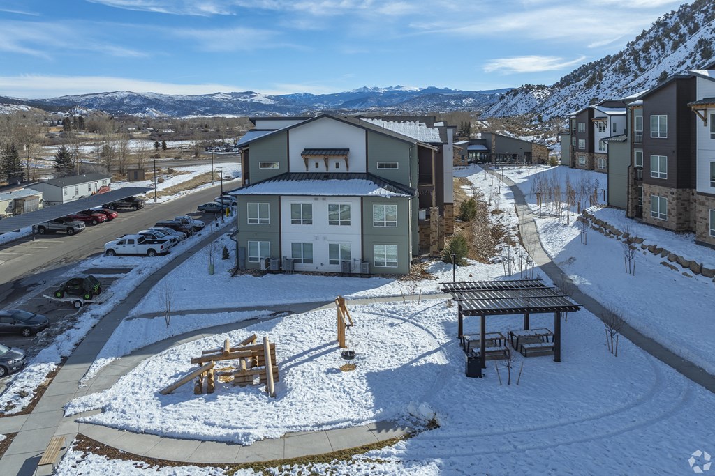 A snowy landscape with a building and a picnic table.