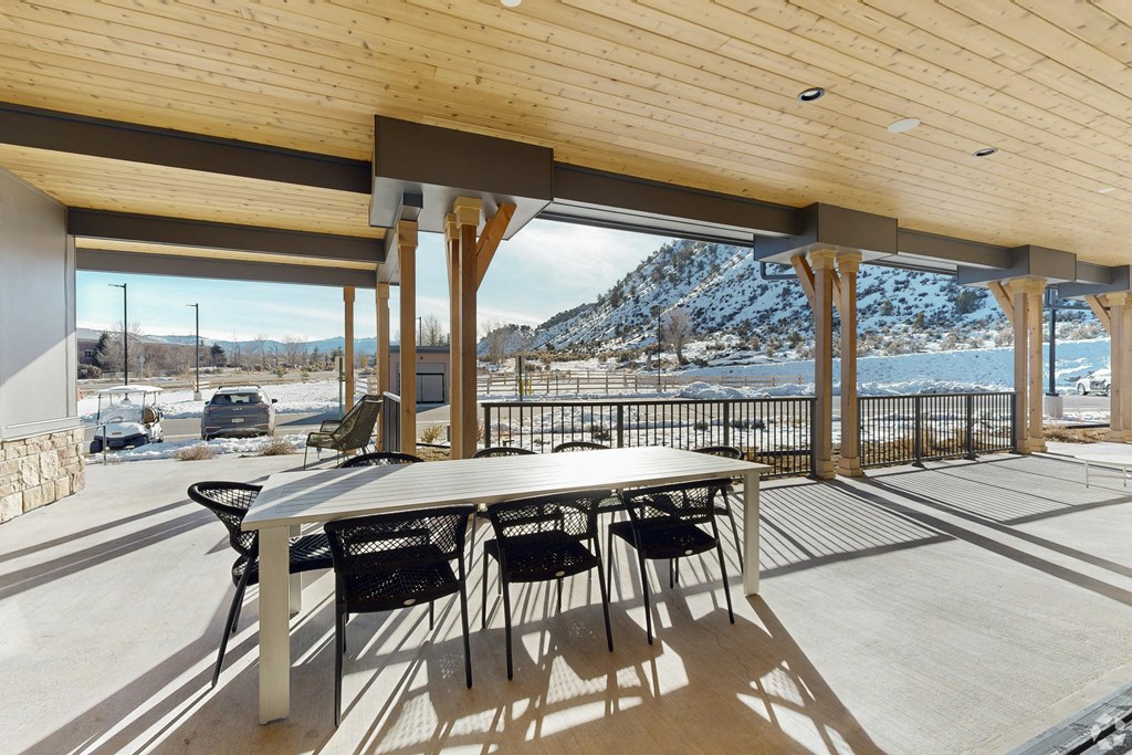 A patio with a table and chairs overlooking a snowy landscape.