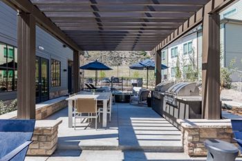 a covered patio with tables and chairs and a grill