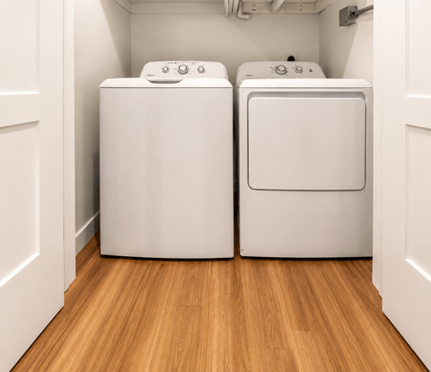 Two white front loading washing machines in a laundry room.