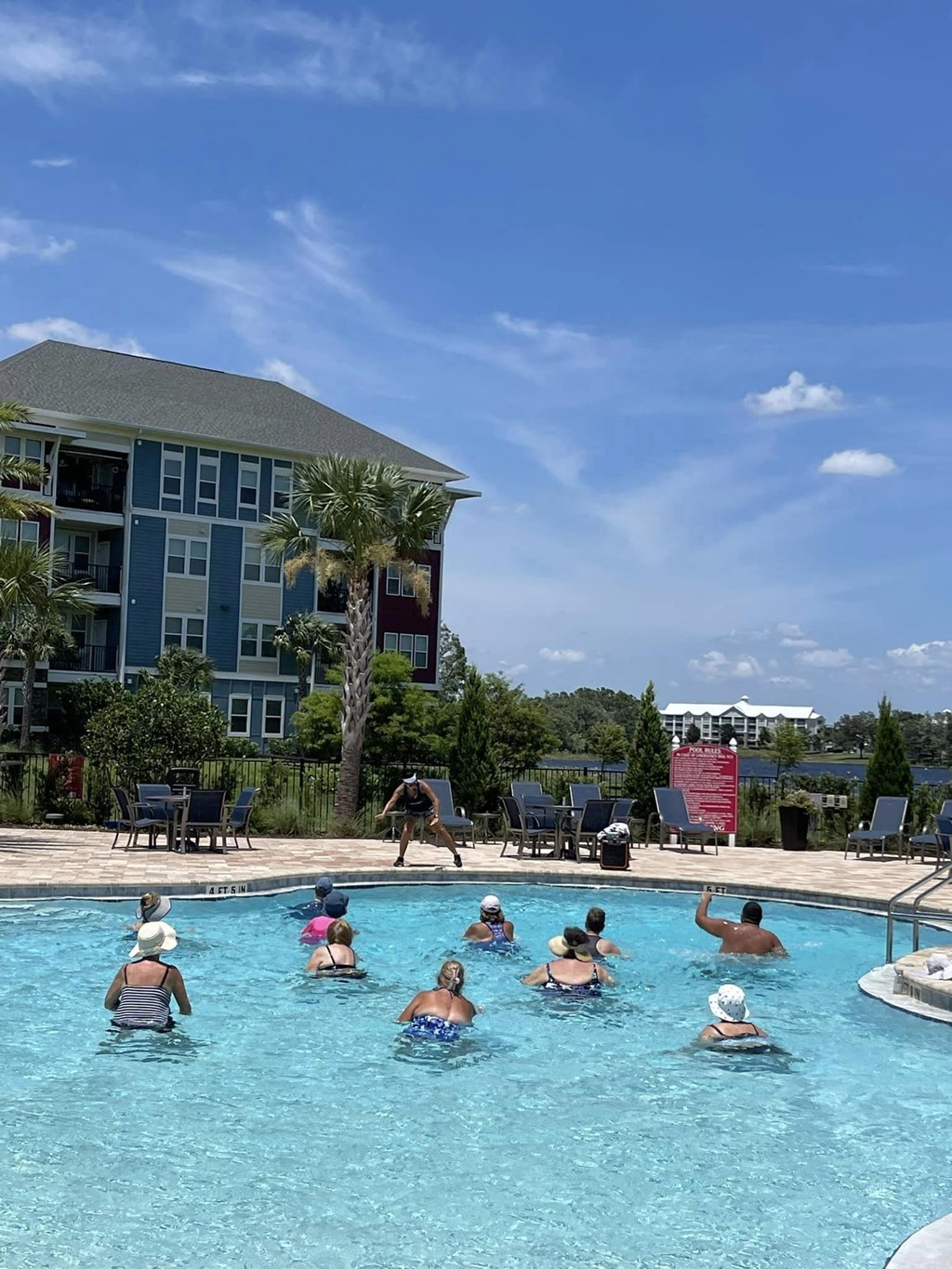 a group of people playing in a pool with a building in the background