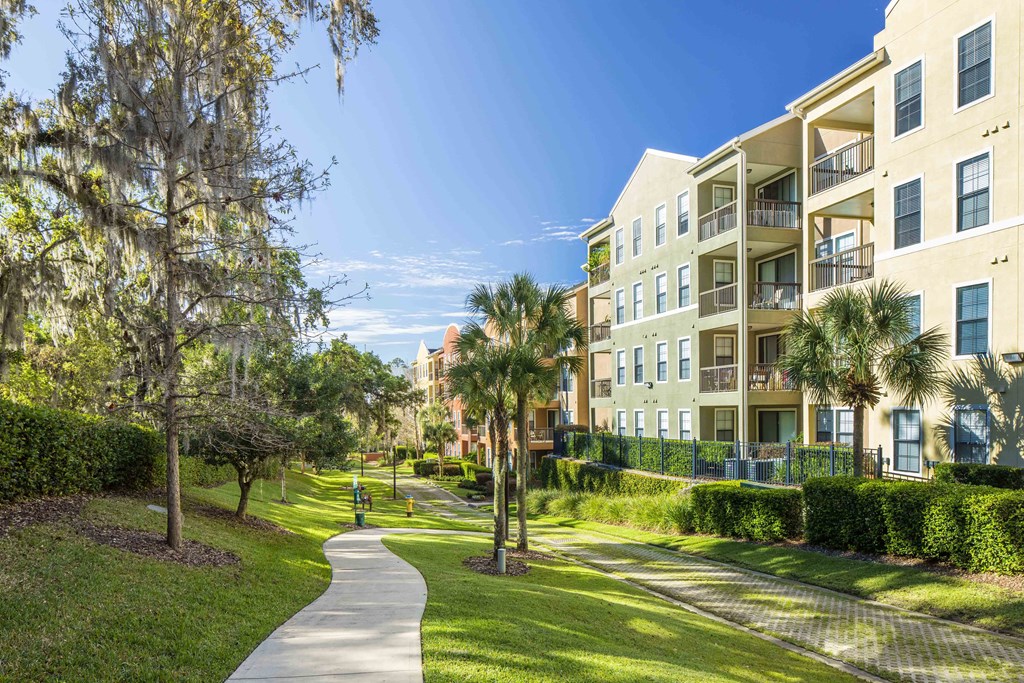 a walkway between apartment buildings with palm trees
