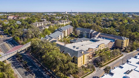 an aerial view of a building with a parking lot and a bridge