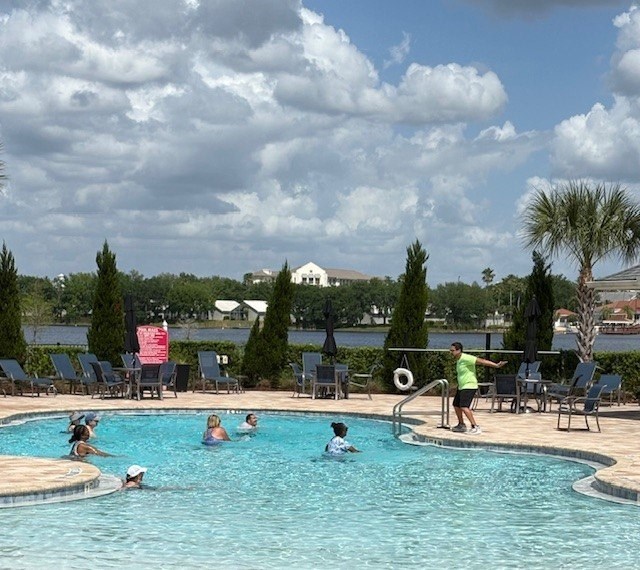 A group of people are enjoying a swim in a pool on a sunny day.