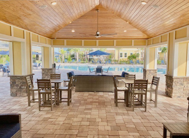 a large patio with tables and chairs and a swimming pool