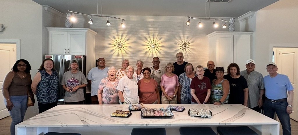 A group of people are gathered around a table with a cake in the middle.