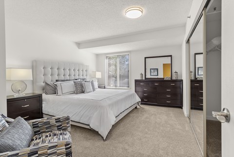 A bedroom with a bed, dresser, and chair.