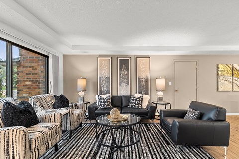 A living room with a black and white striped sofa, a black leather chair, and a coffee table with a glass top.