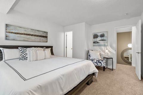 A bedroom with a large bed and a painting on the wall.