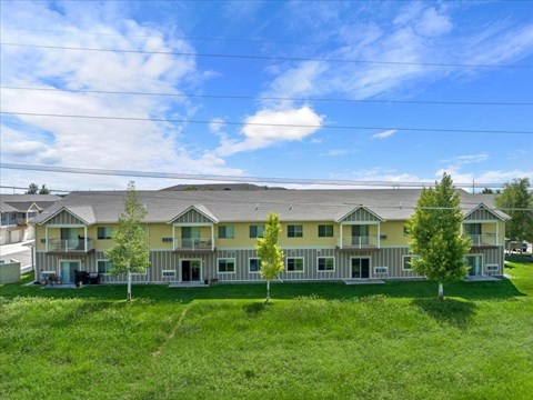 A large, multi-story building with a green lawn in front.