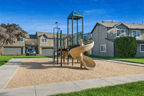 A playground with a yellow slide and a green roofed structure.