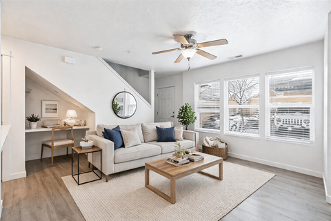 A living room with a couch, a coffee table, and a ceiling fan.