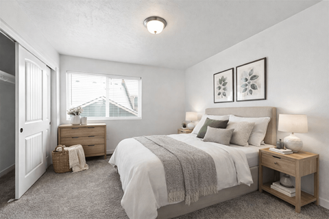 A bedroom with a bed, nightstand, and window.