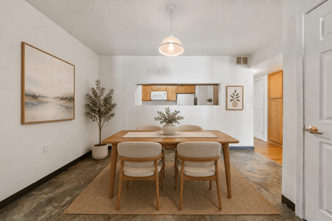 A dining room with a table set for two and a painting on the wall.