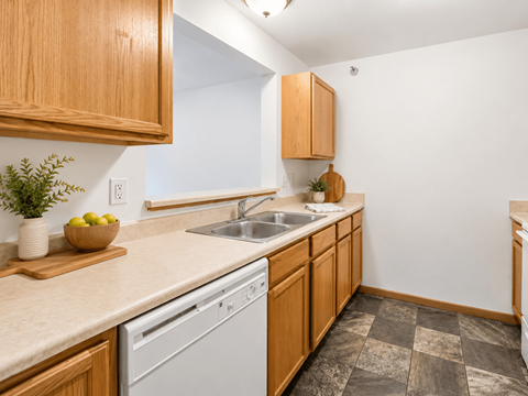 A kitchen with wooden cabinets and a white dishwasher.