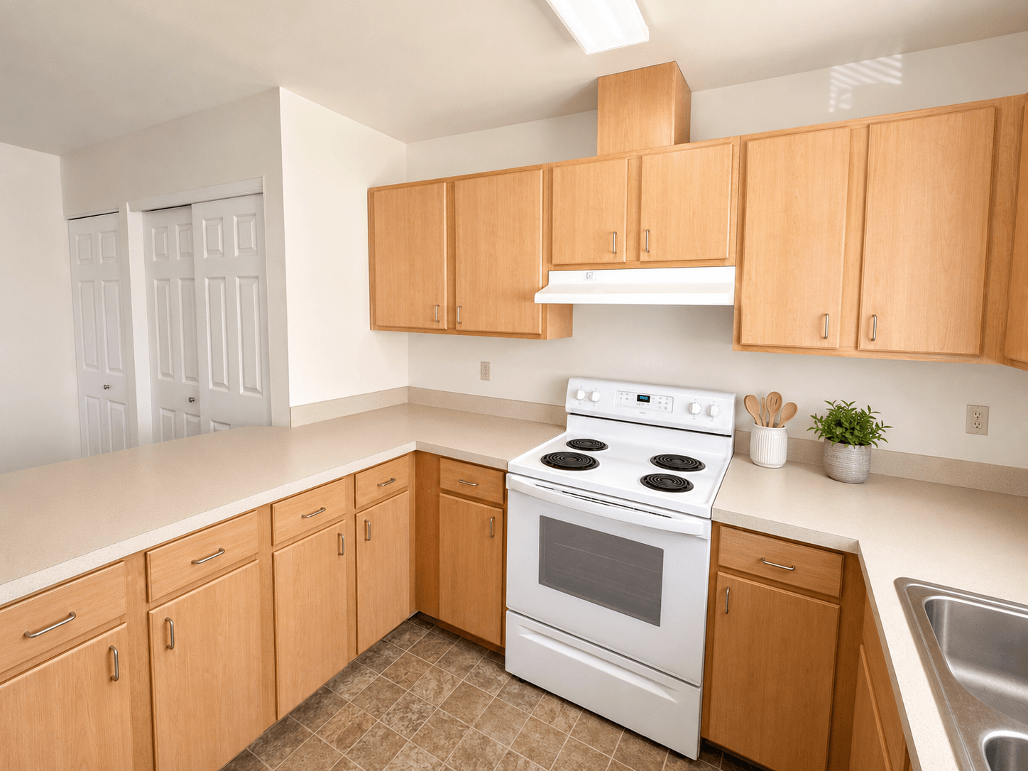 A kitchen with a white stove top oven and wooden cabinets.