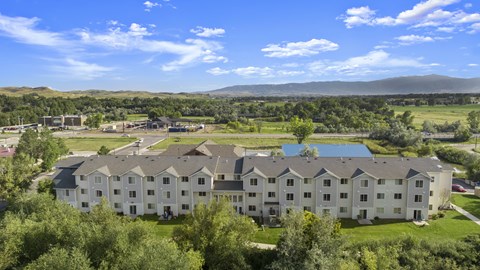 A large white building with a pool in the middle of a green field.
