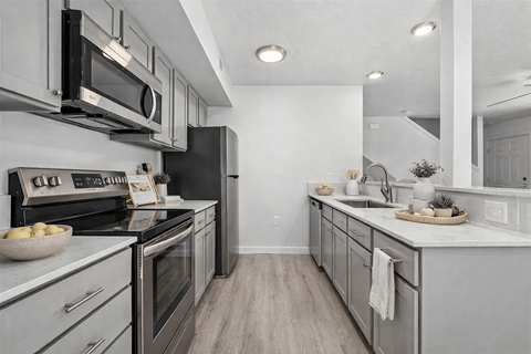 A modern kitchen with a black refrigerator and stove top oven.