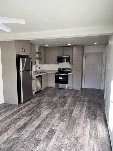 A kitchen with a refrigerator, microwave, oven, and sink.