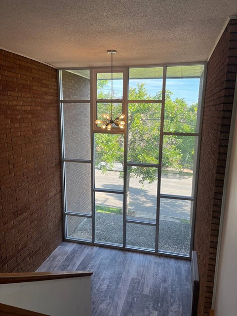 A view of a street through a window with a chandelier hanging from the ceiling.