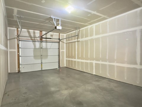 A room with a garage door and a concrete floor.
