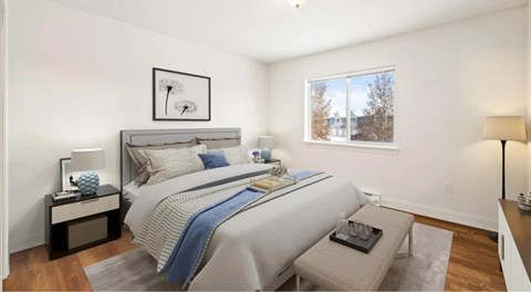 A bedroom with a large bed and a window showing a view of a building outside.