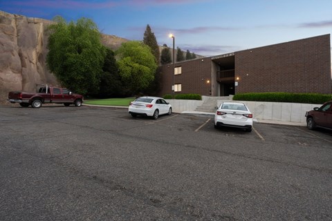 A parking lot with a red truck, a white car, and a brown car.