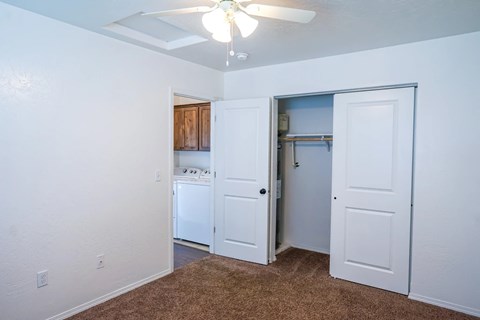 A room with a brown carpet and a ceiling fan.