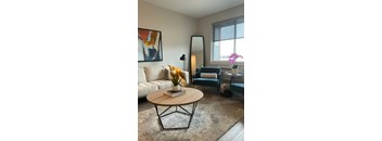 A living room with a white sofa, a coffee table, and a painting on the wall.
