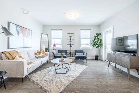 A living room with a white couch, a coffee table, and a television.