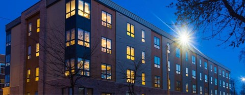 A building with a tree in front of it is illuminated by a bright light.