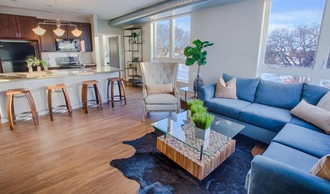 A living room with a blue couch and a glass coffee table.
