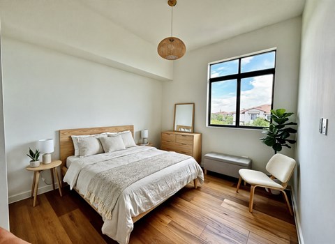 A bedroom with a large bed and a window overlooking a house.