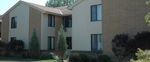 A large brick building with a green lawn in front.