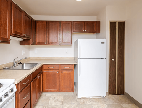 A white refrigerator in a kitchen with wooden cabinets.