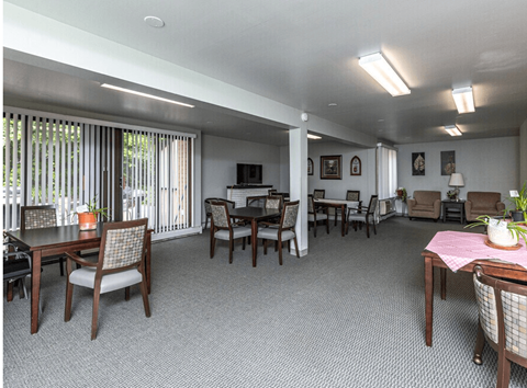 A dining room with a table set for two and chairs around it.