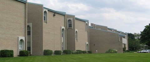 A large brick building with arched windows and a green roof.