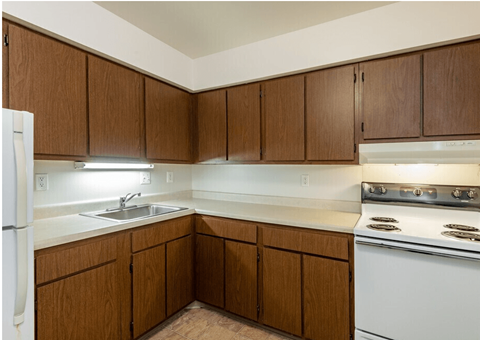 A kitchen with brown cabinets and white appliances.
