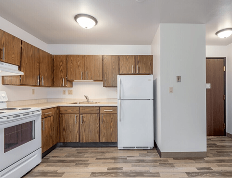 A kitchen with a white fridge and wooden cabinets.