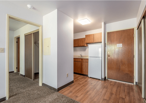 A kitchen area with a white refrigerator and wooden cabinets.