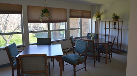 A room with a table and chairs in front of a window.