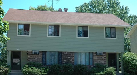 A house with a green siding and a red roof.