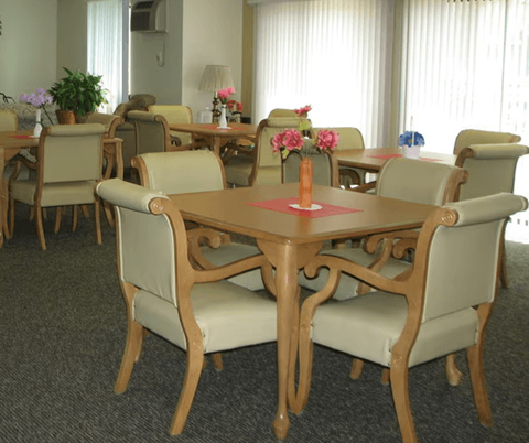 A dining room with a table surrounded by chairs.