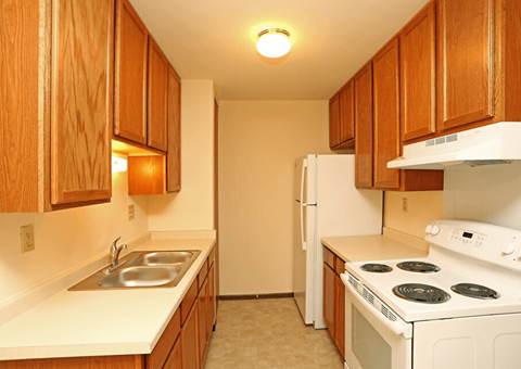 A kitchen with white appliances and wooden cabinets.