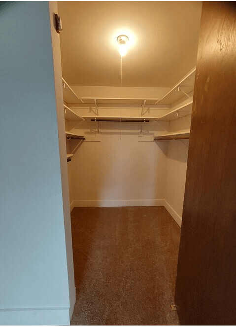 A hallway with a light on the ceiling and a carpeted floor.